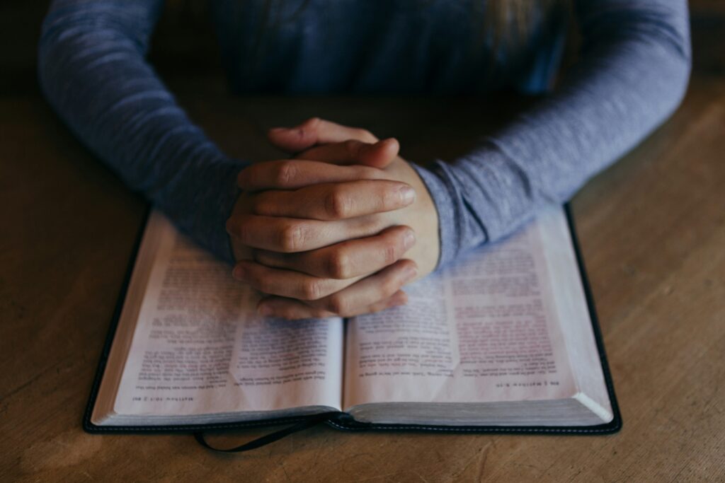 person praying with Bible on table. 